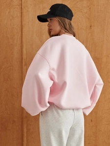 Rear view of oversized light pink crewneck sweatshirt with dropped shoulders and ribbed cuffs