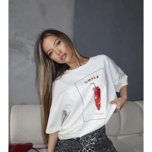 Close-up of red chili print and 'CHILI' lettering on a white cotton T-shirt fabric