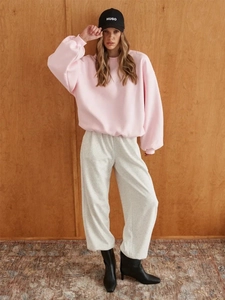 Pink oversized crewneck sweatshirt and grey jogger set styled with a black baseball cap