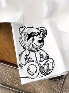 Close-up of a white street-style T-shirt featuring a black graffiti teddy bear print