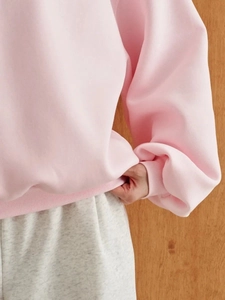 Detailed macro view of the elastic ribbed hem on a thick light pink cotton sweatshirt