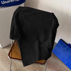 Minimalist black crewneck t-shirt in cotton blend displayed on a modern wooden chair