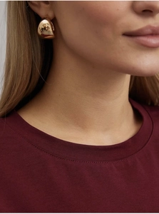 Gros plan de boucles d'oreilles gouttes dorées avec une finition miroir sur un mannequin