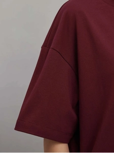 Gros plan sur la couture de l'épaule et le tissu en coton de ce t-shirt oversize bordeaux