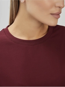 Détail du col rond et de la double couture d'un t-shirt en coton de couleur bordeaux