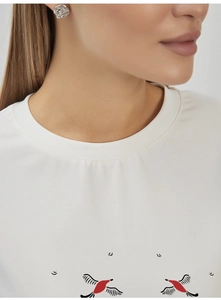 Close-up of white cotton T-shirt neckline and a silver rose earring on model