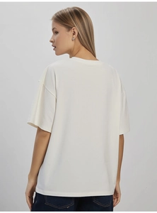 Detail view of the cream white cotton oversized T-shirt back showing loose shoulder fit