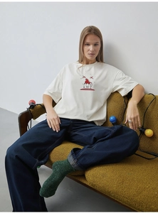 Close-up of red horse embroidery on a cream cotton T-shirt with blue denim jeans
