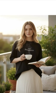 Détail du t-shirt ample en coton noir avec imprimé mood Prosecco sous une lumière chaude