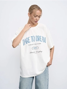 Detail of vintage letter print on oversized cotton tee with DARE TO DREAM slogan