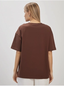 Back view of a loose dark brown cotton T-shirt with dropped shoulders and a minimalist style