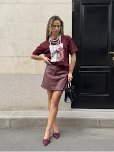 Detailed street style view of wine red letter print T-shirt and matching leather skirt