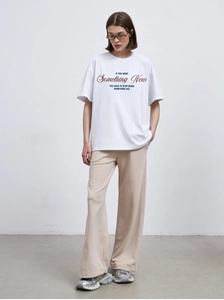 Detail of white cotton T-shirt with red letter print paired with beige wide-leg trousers