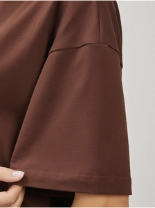 Close-up of double-needle stitching on the drop shoulder of a brown cotton t-shirt