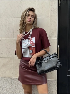 Detail of burgundy T-shirt with art print paired with matching leather skirt and pearls
