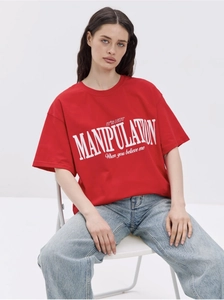 Close-up of red oversized cotton T-shirt featuring white MANIPULATION letter print