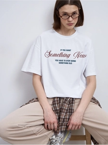 Close-up of oversized white cotton t-shirt featuring navy blue 'Something New' slogan