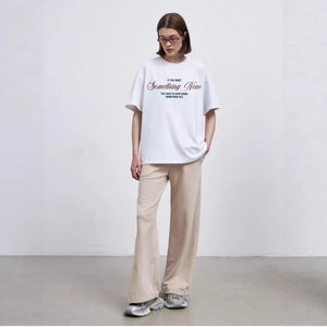 Oversized white T-shirt with motivational print paired with beige wide-leg trousers