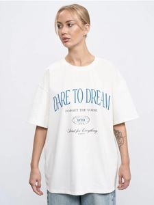 Close-up of DARE TO DREAM blue letter print on premium white oversized cotton t-shirt