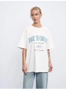 Detail of oversized cream cotton t-shirt with blue DARE TO DREAM graphic lettering