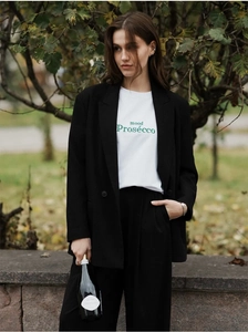 Détail d'un t-shirt en coton blanc avec imprimé vert sous un blazer noir surdimensionné