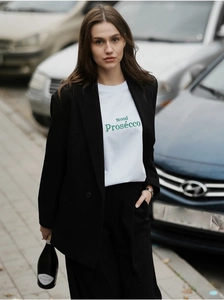 Détail d'un t-shirt en coton blanc avec lettrage Prosecco vert sous un blazer noir