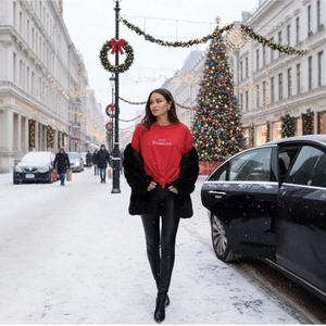 Women's winter outfit with red Prosecco tee, black faux fur coat and leather pants in snow