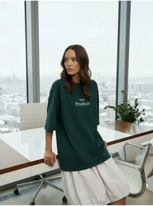 Gros plan d'un t-shirt oversize vert foncé avec l'imprimé texte mood Prosecco blanc
