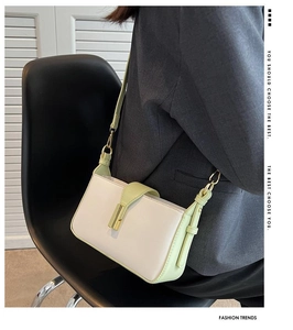 Détail du sac bandoulière crème et vert clair avec fermoir doré porté par un mannequin