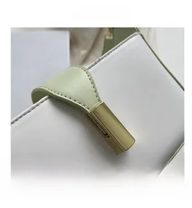 Détail de la sangle en cuir vert clair avec boucle rectangulaire dorée sur un sac à main blanc