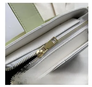 Détail de la fermeture éclair dorée lisse sur le sac à bandoulière en cuir blanc