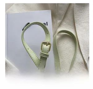 Gros plan d'une bandoulière en cuir vert clair avec boucle en métal doré ajustable