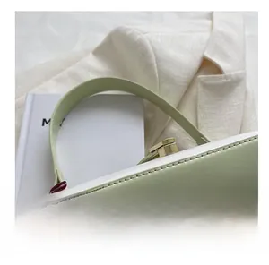 Détail du sac sous le bras blanc brillant avec bandoulière vert clair et boucle métal
