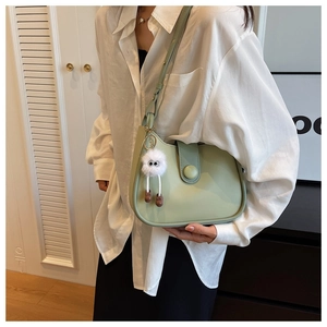 Detail of light green crescent underarm bag with a plush charm and decorative buckle