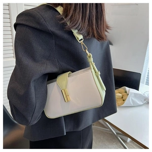 Détail du sac à bandoulière crème minimaliste avec sangle verte porté par un modèle