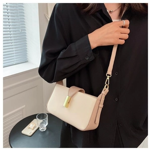 Détail d'un sac à bandoulière crème avec lanière rose et boucle en métal doré chic