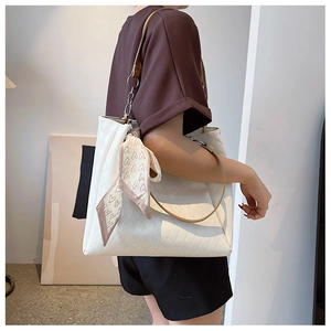 Close-up of quilted white tote bag featuring a pink heart scarf and chain strap