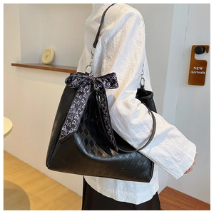 Close-up of black quilted tote bag featuring a heart-print scarf and chain strap detail