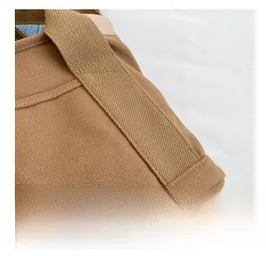 Detailed close-up showing high-density stitching on the brown canvas shoulder bag fabric