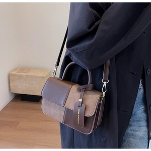Details der braunen Patchwork-Umhängetasche aus Leder mit modischem Anhänger und Griff