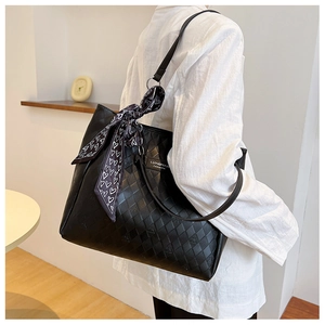 Detail view of black quilted tote bag featuring a heart print silk scarf on the strap