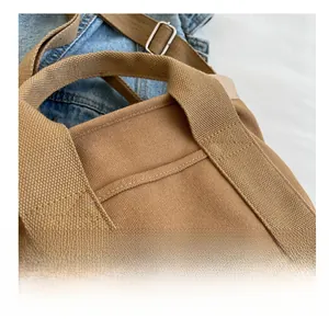Detail of brown canvas tote showing durable top handles and adjustable metal buckle
