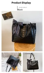 Detail of black quilted tote bag with floral scarf handle and gold hardware buckles