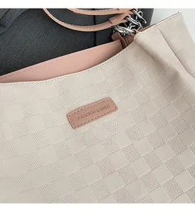 Close-up of beige tote bag with checkered texture and pink leather fashion logo tag