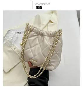 Detail of cream white quilted bucket bag with gold chain strap and elegant pleated closure