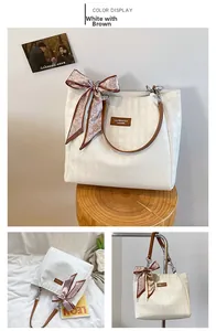 Detailed view of white tote bag with brown straps, diamond pattern and heart scarf