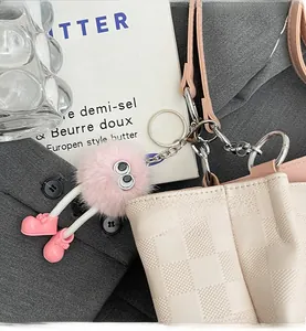 Pink plush ball charm with big eyes and small boots on a checkered tote bag