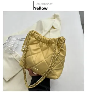 Detail of yellow quilted chain bucket bag with drawstring closure and metal ball decor