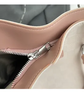 Close-up of the smooth silver zipper and cream embossed woven texture of the tote bag