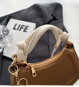 Détail du sac selle marron avec poignée nouée crème unique et fermeture éclair dorée élégante